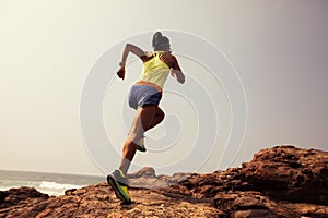 trail runner running to rocky mountain top on seaside