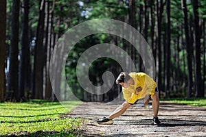 Trail runner is stretching for warm up outdoor in the pine forest dirt road for exercise and workout activities training for