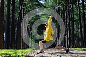 Trail runner is stretching for warm up outdoor in the pine forest dirt road for exercise and workout activities training for