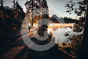 Trail runner in wild nature by lake, gold morning light in background