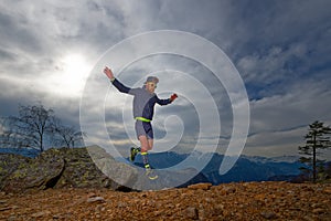 Trail running athlete jumps between the rocks
