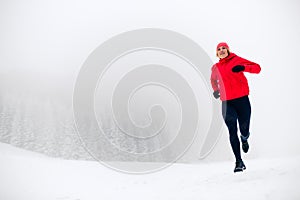 Trail running woman on snow in winter mountains