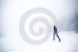 Trail running woman on snow in winter mountains