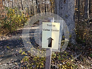 Trail to visitor sign with trail in woods