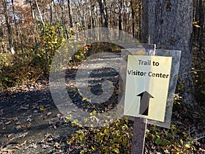 Trail to visitor sign with trail in woods