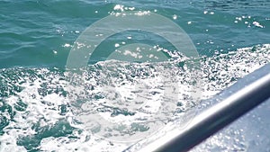 Trail water blue sea surface behind floating ship with foam and waves close up. Trail sea water with , spills, bubbles