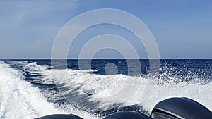 Sea wake trail behind a speed boat with waves, foam, bubbles on the ocean water surface with clear bright blue sky