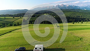 Trailer Caravaning in the mountains. Aerial view of RV car with trailer caravan, parked in the middle of mountain meadow
