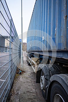 Trailer with freight container parked close to a fence and pole..