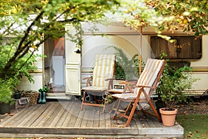 Two deckchairs near outside caravan trailer. Cozy Campsite on caravan or camper van in forest.