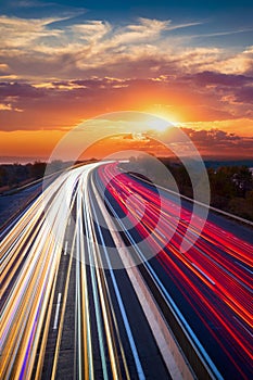 Trails  of cars lights on the asphalt car road. Sunset time with clouds and sun. Drive forward! Transport creative background.