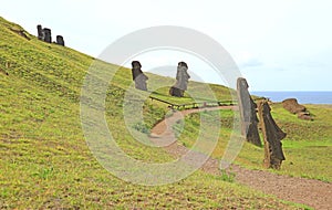 Trails among mountain slope full of abandoned giant Moai statues on Rano Raraku volcano with Pacific ocean, Easter Island