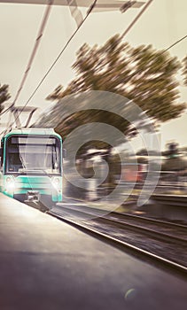 The train arrives quickly at the station with the lights on