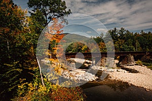 Train bridge over a river and autumn color near Bethel, Maine.