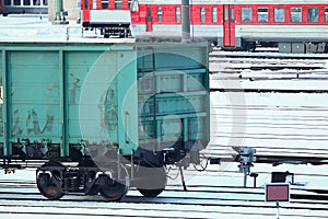 Train carriage standing on dark rails on snow in winter with trains on background