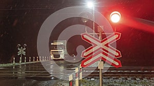 Train crossing gates closed at night. Train grade crossing with blinking or flashing lights while train is moving past