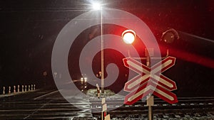 Train crossing gates closed at night. Train grade crossing with blinking or flashing lights while train is moving past