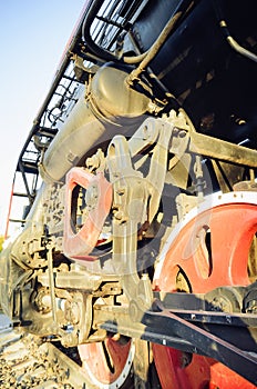 Train drive mechanism and red wheels of an old soviet steam locomotive. Vertical photography