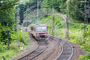 Train driving through woods near river Moselle in Germany