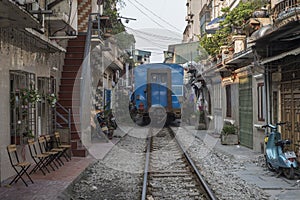 Train goes through a tiny street with locals and tourists in Ha Noi, Viet Nam