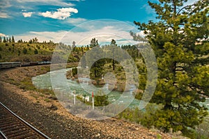 Train going down tracks near a river