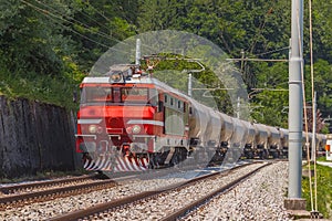 Train hauling waggons with cement. Freight train with a long series of cement carriages traveling on a curved stretch of a track