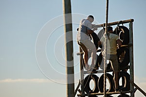 Train like theres no finish line. Shot of men climbing over an obstacle at bootcamp.
