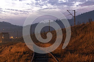 Train line approaching a bridge at sunset whit dark sky