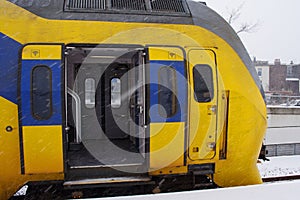 Train with open doors during snowfall