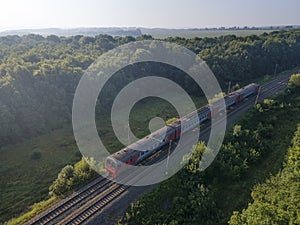 Train on Railroad in summer forest in foggy sunrise. Top Aerial view rural railway