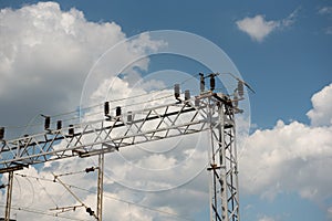 Train or railway power line support. Railway power lines with high voltage electricity on metal poles against blue sky.