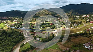 Train rides on old bridge viaduct among mountains and villages aerial drone view