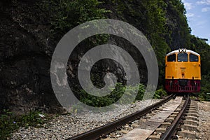 Train running on track between hellfire pass mountain and riverside Sai Yok waterfall and Khwae river bring thai people and