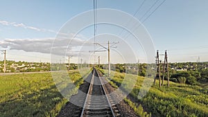 Train slowly rides on the railway against the beautiful landscape and green grass and blue clear sky during sunset