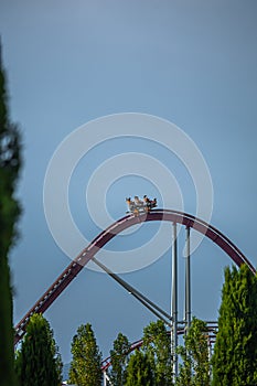 The train with some people is riding on roller coaster during a cloudy weather