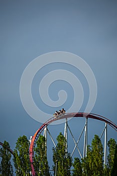 The train with some people is riding on roller coaster during a cloudy weather