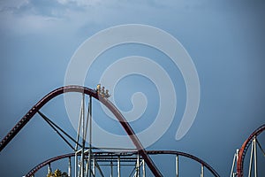 The train with some people is riding on roller coaster during a cloudy weather