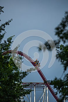 The train with some people is riding on roller coaster during a cloudy weather