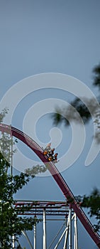 The train with some people is riding on roller coaster during a cloudy weather