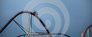 The train with some people is riding on roller coaster during a cloudy weather