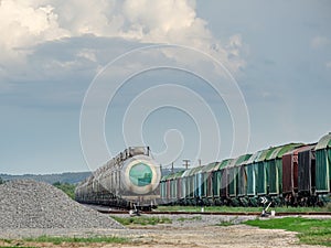 Train standing on siding on a sunny day in summer. Railway freight wagons and tanks of a different type and color