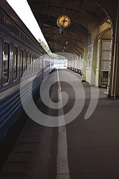 The train stands on the platform before departure, passengers are already in the carriage, an empty platform with a clock