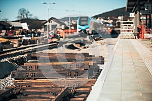 Train station of Grosuplje under construction. Visible wooden railway sleepers ready to be installed. Modern train waiting in the