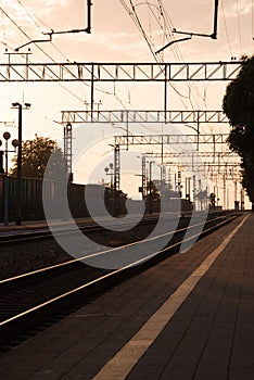 Train station at sunset. Rails that go off into the distance. The silhouettes of the pillars.