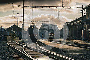 Train station in switzerland, frontal view of the train and train tracks in strong evening sunset light. Typical branch line