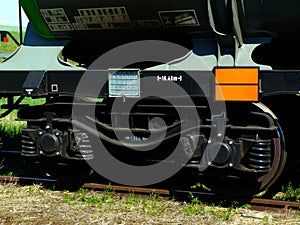 Train steel wheels close-up with overgrown steel rails