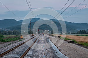 Train track renovation. Twin rail tracks of which one is dismantled, upper layer removed and being renewed. Modern railway track