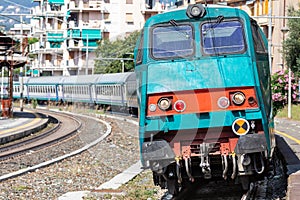 Train on tracks arriving in transit at the railway station. Public transport on rails. At a station in Liguria in northern Italy.