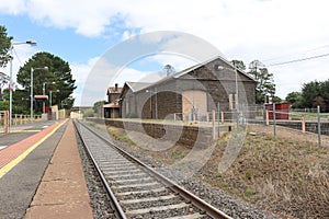 train tracks and a bluestone railway station building and platform