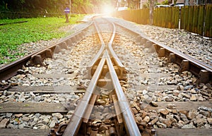 Train tracks on gravel, two of railways tracks merge  with sunset background, concept of success photo
